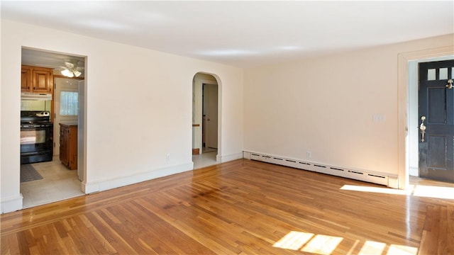 92 Glendale Dr, West Warwick, RI 02893 - spare room featuring baseboard heating, arched walkways, light wood-type flooring, and a ceiling fan