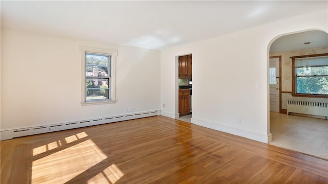 92 Glendale Dr, West Warwick, RI 02893 - spare room featuring radiator heating unit, a baseboard radiator, arched walkways, and light wood-style flooring