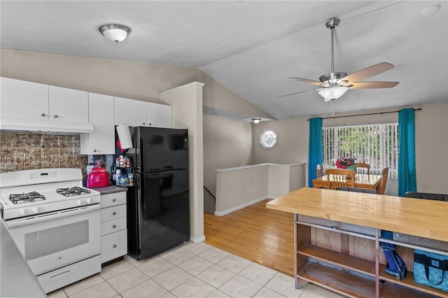 4 Clarke St, Warwick, RI 02886 - kitchen featuring white range with gas stovetop, freestanding refrigerator, light tile patterned flooring, under cabinet range hood, and lofted ceiling