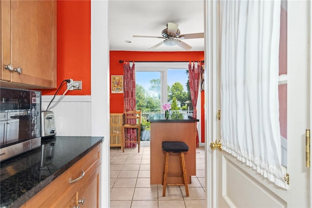 161 Ferncrest Ave, Cranston, RI 02905 - kitchen featuring stainless steel microwave, a wainscoted wall, light tile patterned floors, ceiling fan, and brown cabinets