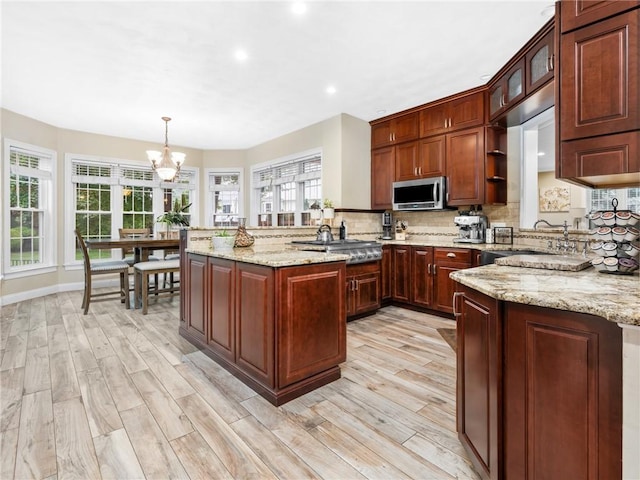 2 Medinah Dr, West Warwick, RI 02893 - kitchen featuring stainless steel microwave, a peninsula, a chandelier, tasteful backsplash, and healthy amount of natural light