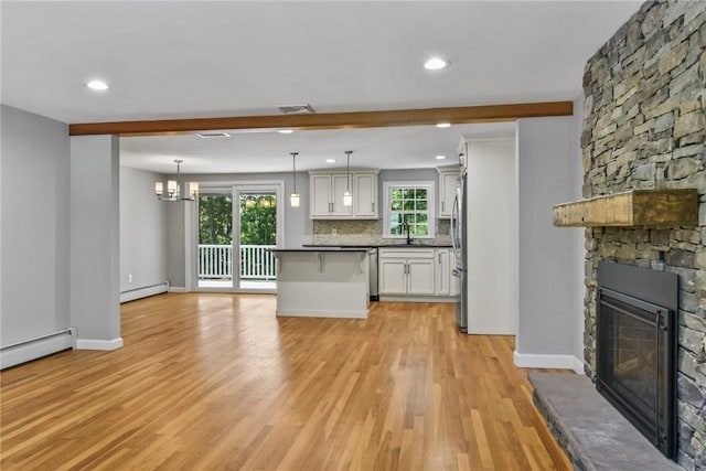 88 Grand View Rd, East Greenwich, RI 02818 - kitchen with a baseboard heating unit, freestanding refrigerator, dark countertops, a stone fireplace, and light wood finished floors