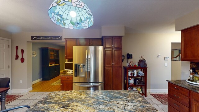 4 Tray Hollow Rd, Foster, RI 02825 - kitchen featuring stainless steel fridge with ice dispenser, light tile patterned floors, dark stone counters, and reddish brown cabinets