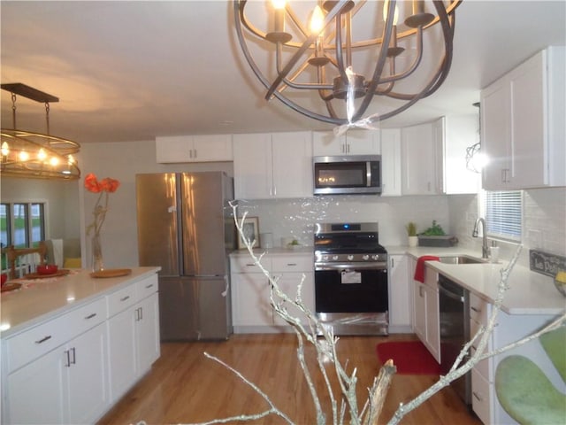 155 Lewiston St, Warwick, RI 02889 - kitchen with appliances with stainless steel finishes, a chandelier, light wood finished floors, white cabinetry, and light countertops