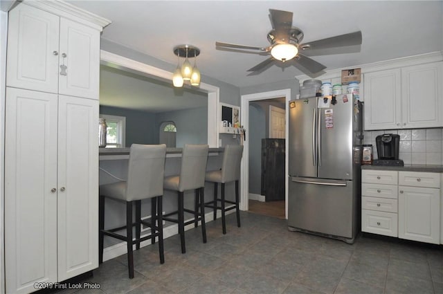 62 Stone Ave, Warwick, RI 02889 - kitchen with freestanding refrigerator, white cabinetry, a ceiling fan, and backsplash