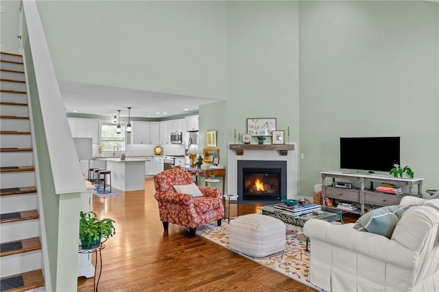 83 Silas Hill Way, Exeter, RI 02822 - living room featuring stairs, wood finished floors, a high ceiling, and a glass covered fireplace