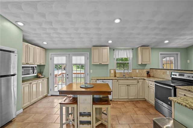 273 Main St, Cranston, RI 02823 - kitchen featuring stainless steel appliances, cream cabinetry, french doors, a kitchen breakfast bar, and light tile patterned floors