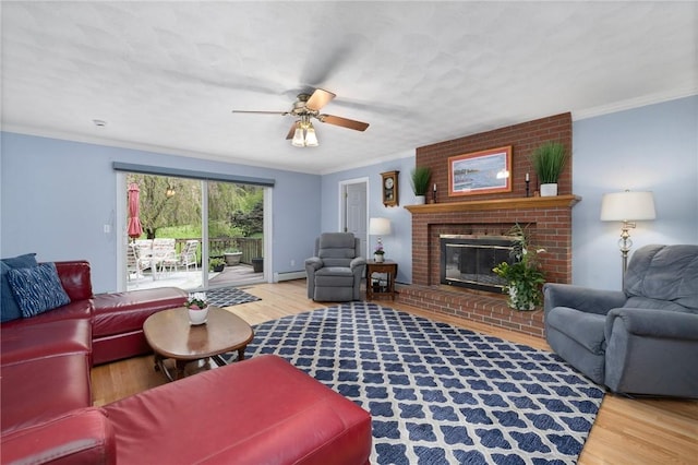 34 Finch Ln, North Kingstown, RI 02874 - living area with wood finished floors, ceiling fan, a baseboard heating unit, a brick fireplace, and crown molding