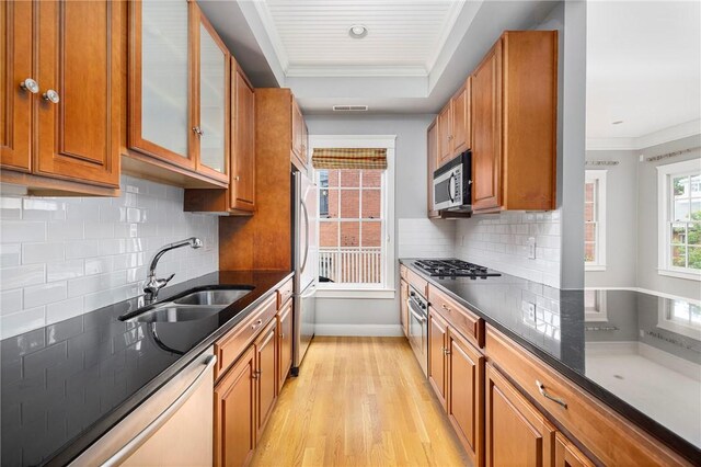 279 Benefit St Unit 3, Providence, RI 02903 - kitchen featuring appliances with stainless steel finishes, brown cabinets, light wood finished floors, decorative backsplash, and ornamental molding