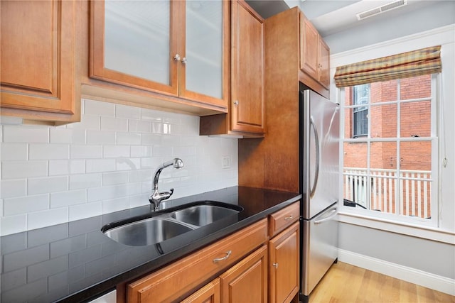 279 Benefit St Unit 3, Providence, RI 02903 - kitchen with freestanding refrigerator, tasteful backsplash, light wood finished floors, glass insert cabinets, and brown cabinets