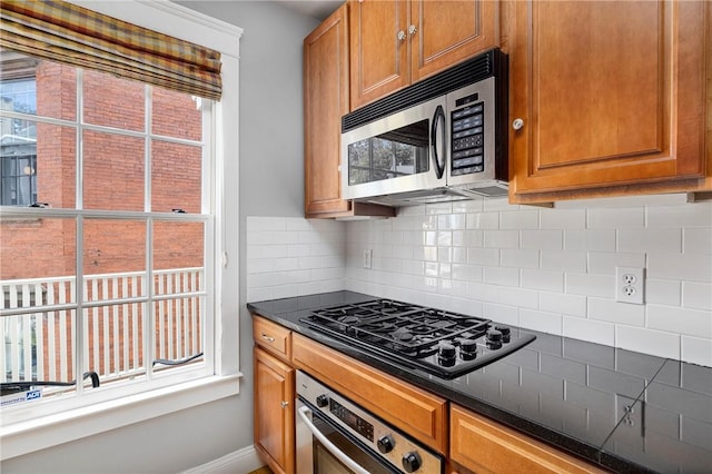 279 Benefit St Unit 3, Providence, RI 02903 - kitchen featuring stainless steel appliances, backsplash, dark countertops, and brown cabinetry