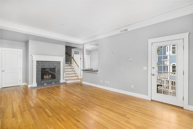279 Benefit St Unit 3, Providence, RI 02903 - unfurnished living room with light wood-style flooring, ornamental molding, a tiled fireplace, and stairs