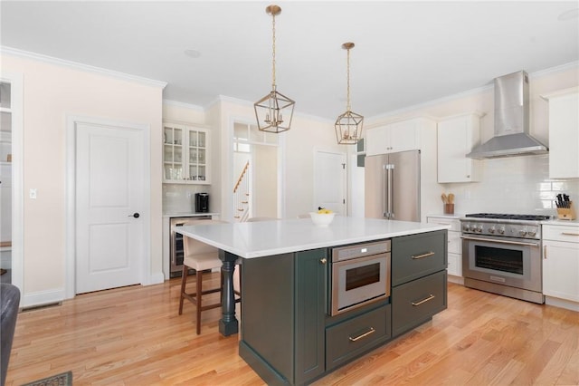9 Scarlett Way, Cranston, RI 02921 - kitchen featuring wall chimney range hood, premium appliances, wine cooler, white cabinetry, and backsplash