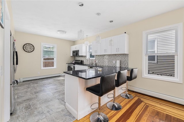 2 Palfrey Pl, Providence, RI 02909 - kitchen featuring gas stove, a baseboard radiator, a breakfast bar, white cabinetry, and a baseboard heating unit