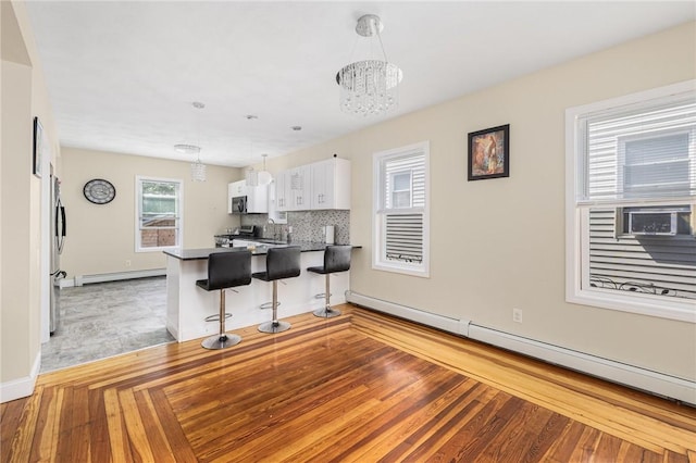 2 Palfrey Pl, Providence, RI 02909 - kitchen with a baseboard radiator, a baseboard heating unit, a chandelier, dark countertops, and white cabinets