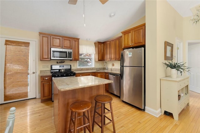 104 Conanicus Rd, Narragansett, RI 02882 - kitchen featuring stainless steel appliances, light wood-style flooring, a kitchen island, lofted ceiling, and brown cabinets