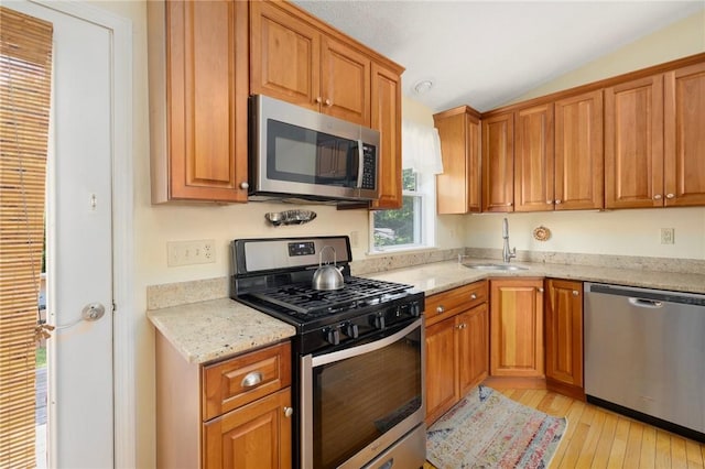 104 Conanicus Rd, Narragansett, RI 02882 - kitchen featuring appliances with stainless steel finishes, lofted ceiling, light wood-style flooring, light stone countertops, and brown cabinets