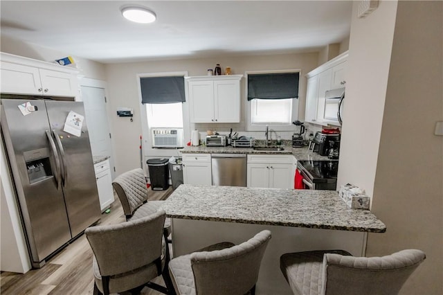 25 Unit St, Providence, RI 02909 - kitchen with stainless steel appliances, a peninsula, light wood-style floors, and white cabinetry