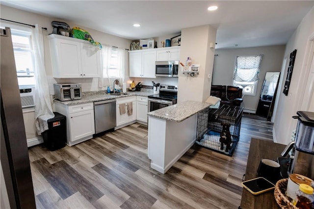 25 Unit St, Providence, RI 02909 - kitchen featuring appliances with stainless steel finishes, white cabinets, light stone countertops, wood finished floors, and recessed lighting