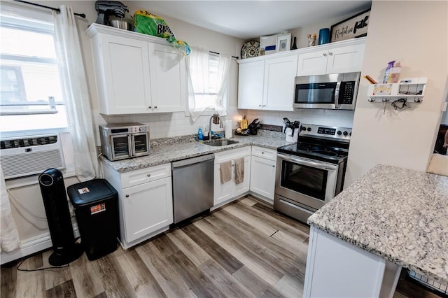 25 Unit St, Providence, RI 02909 - kitchen featuring stainless steel appliances, white cabinetry, backsplash, and light wood-style floors