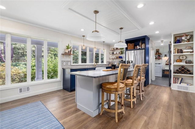 469 Fletcher Rd, North Kingstown, RI 02852 - kitchen featuring open shelves, washer / dryer, stainless steel refrigerator with ice dispenser, wood finished floors, and a breakfast bar area