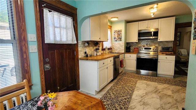 788 Cass Ave, Woonsocket, RI 02895 - kitchen with stainless steel appliances, decorative backsplash, arched walkways, and wood counters