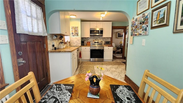 788 Cass Ave, Woonsocket, RI 02895 - kitchen featuring stainless steel appliances, arched walkways, white cabinetry, backsplash, and wood counters