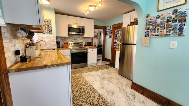 788 Cass Ave, Woonsocket, RI 02895 - kitchen with stainless steel appliances, wooden counters, white cabinetry, and arched walkways
