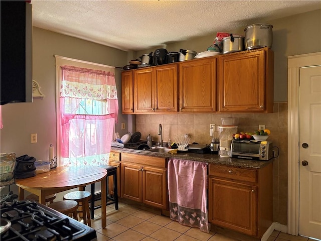 282 Oxford St, Providence, RI 02905 - kitchen with light tile patterned floors, brown cabinets, dark countertops, a textured ceiling, and decorative backsplash