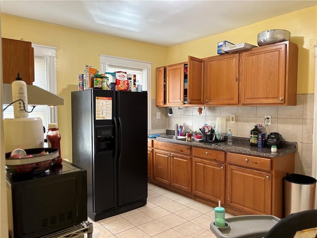 282 Oxford St, Providence, RI 02905 - kitchen with black fridge, brown cabinets, light tile patterned flooring, dark countertops, and backsplash