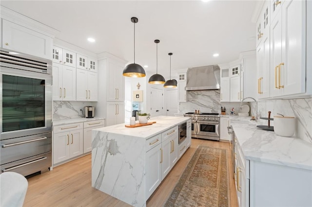 3 Kelsey Eden Way, Cumberland, RI 02864 - kitchen featuring wall chimney range hood, premium appliances, a kitchen island, tasteful backsplash, and white cabinetry