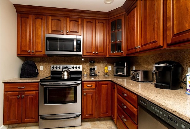 136 Woodward Rd, Providence, RI 02904 - kitchen featuring appliances with stainless steel finishes, light stone countertops, tasteful backsplash, and glass insert cabinets