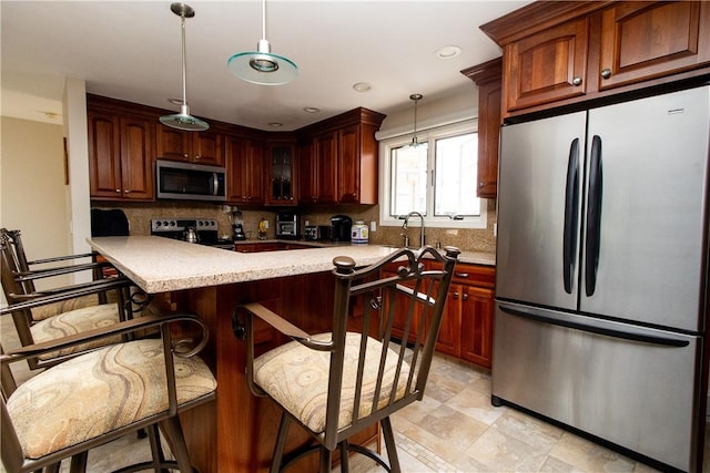 136 Woodward Rd, Providence, RI 02904 - kitchen with appliances with stainless steel finishes, decorative backsplash, light countertops, decorative light fixtures, and a breakfast bar area
