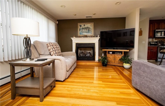 136 Woodward Rd, Providence, RI 02904 - living area with light wood-type flooring, a fireplace with raised hearth, recessed lighting, and a baseboard radiator