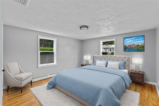 22 Hillcrest Dr, West Warwick, RI 02893 - bedroom featuring a baseboard radiator, multiple windows, light wood-style floors, and a textured ceiling