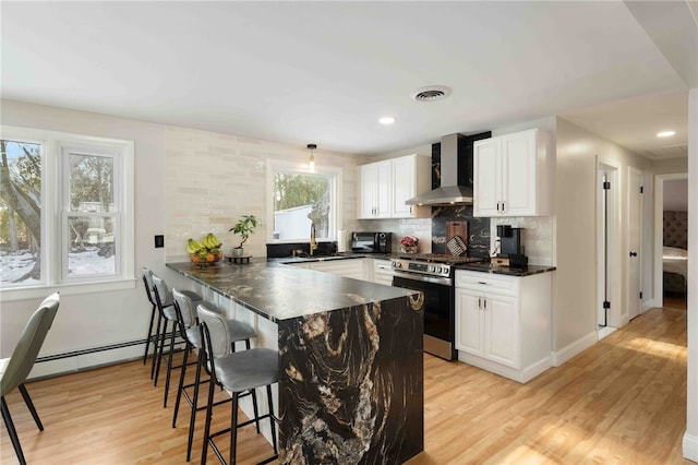 6 Flanders St, Johnston, RI 02919 - kitchen with stainless steel range with gas stovetop, wall chimney exhaust hood, a peninsula, light wood-style flooring, and a kitchen breakfast bar