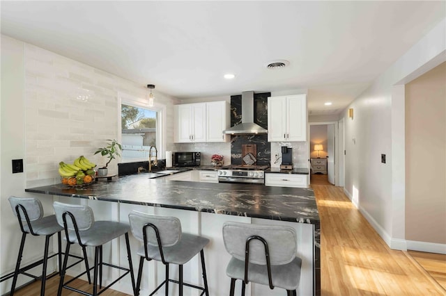 6 Flanders St, Johnston, RI 02919 - kitchen with wall chimney range hood, stainless steel electric range, a peninsula, dark countertops, and white cabinets