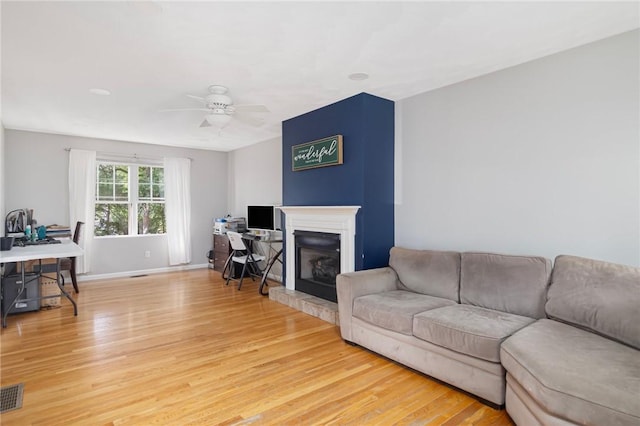 29 Gilcrest Dr, West Warwick, RI 02893 - living room with light wood finished floors, a ceiling fan, a desk, and a fireplace with raised hearth