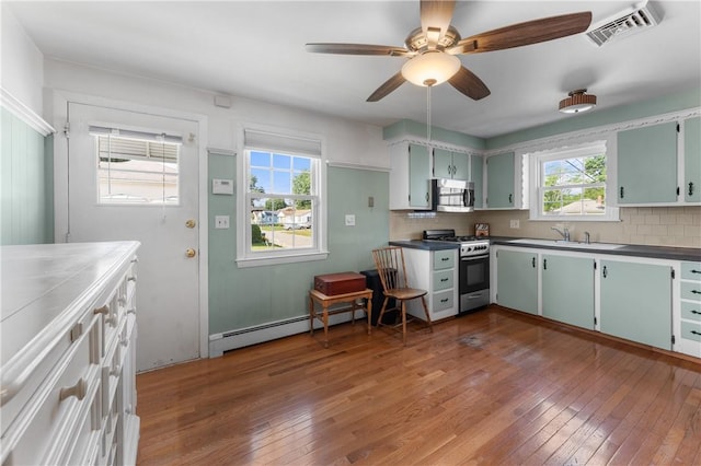59 Waite St, Providence, RI 02908 - kitchen featuring appliances with stainless steel finishes, baseboard heating, backsplash, and hardwood / wood-style floors