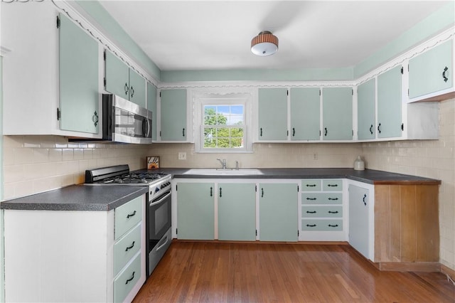 59 Waite St, Providence, RI 02908 - kitchen featuring appliances with stainless steel finishes, wood finished floors, dark countertops, and decorative backsplash
