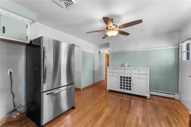59 Waite St, Providence, RI 02908 - kitchen with freestanding refrigerator, a baseboard heating unit, ceiling fan, wood finished floors, and white cabinets
