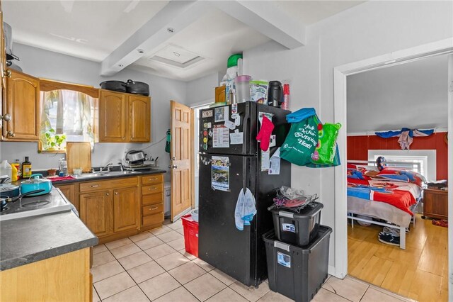 18 Ortoleva Dr, Providence, RI 02909 - kitchen featuring freestanding refrigerator, light tile patterned flooring, beamed ceiling, brown cabinetry, and dark countertops