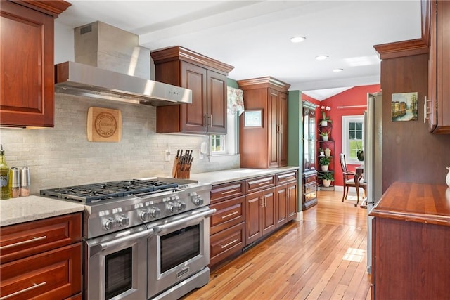 12 Windward Cir, Warwick, RI 02889 - kitchen featuring range with two ovens, wall chimney range hood, decorative backsplash, light wood-type flooring, and lofted ceiling