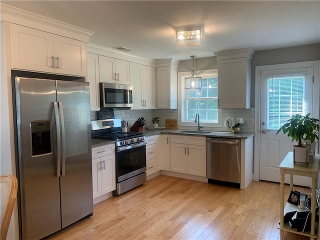 20 Winston Way, Johnston, RI 02919 - kitchen with appliances with stainless steel finishes, light wood finished floors, backsplash, dark stone counters, and pendant lighting