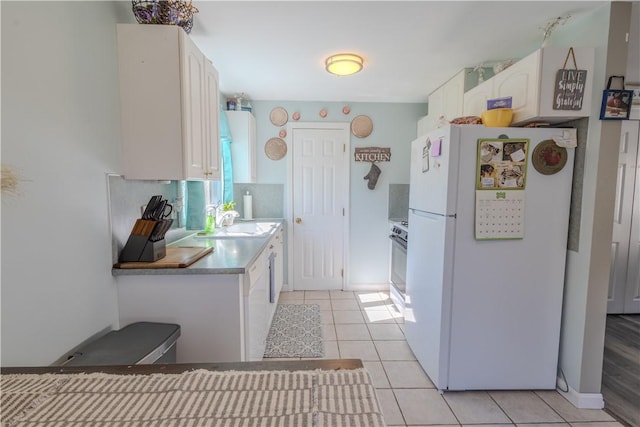 151 Willet Ave Unit 5, East Providence, RI 02915 - kitchen with freestanding refrigerator, light tile patterned flooring, white cabinetry, and stove
