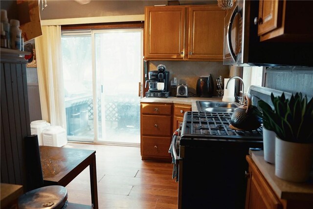 23 Majestic Ave, Warwick, RI 02888 - kitchen featuring stainless steel appliances, brown cabinetry, light countertops, light wood-style floors, and decorative backsplash