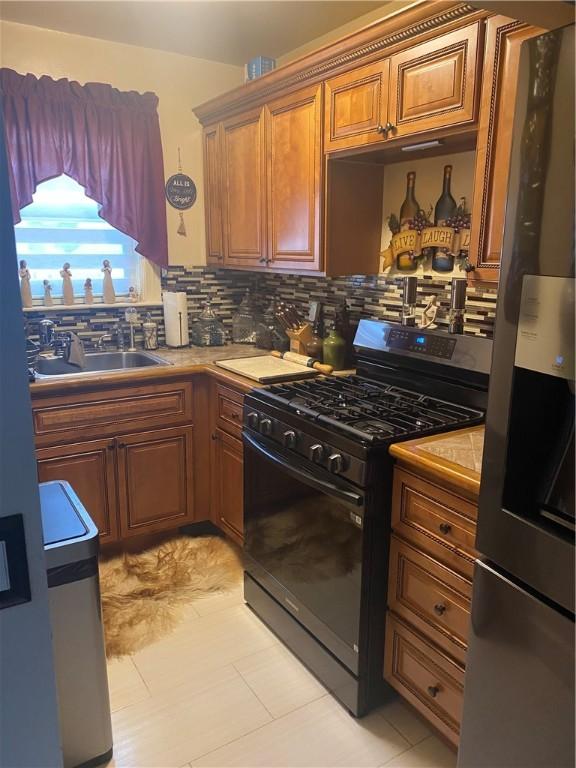 26 Anchor St, Providence, RI 02908 - kitchen with gas stove, stainless steel fridge with ice dispenser, decorative backsplash, brown cabinets, and light tile patterned floors
