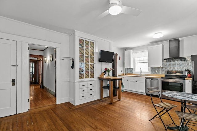 32 Thurston Ave Unit A, Newport, RI 02840 - kitchen with wall chimney exhaust hood, stainless steel appliances, tasteful backsplash, hardwood / wood-style flooring, and white cabinets