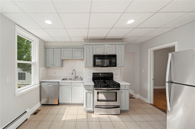 65 Lancaster St Unit 1, Providence, RI 02906 - kitchen featuring appliances with stainless steel finishes, baseboard heating, light countertops, decorative backsplash, and a drop ceiling