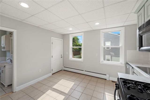 65 Lancaster St Unit 1, Providence, RI 02906 - kitchen with gas stove, a baseboard heating unit, light countertops, a paneled ceiling, and light tile patterned flooring
